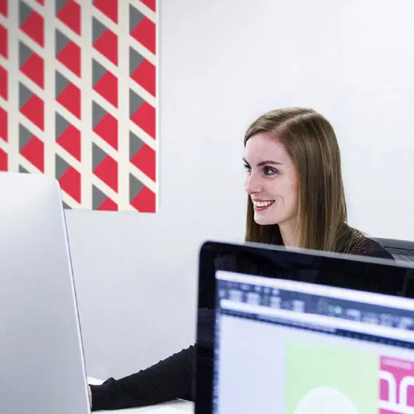 Smiling woman sitting at a computer working on a website design