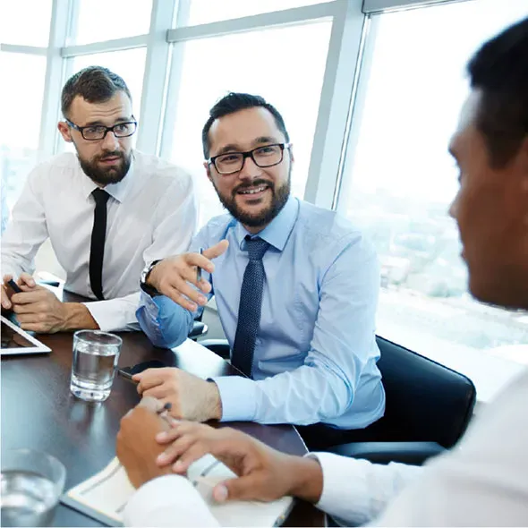 Two men in glasses wearing business shirts looking at a third man who is in profile